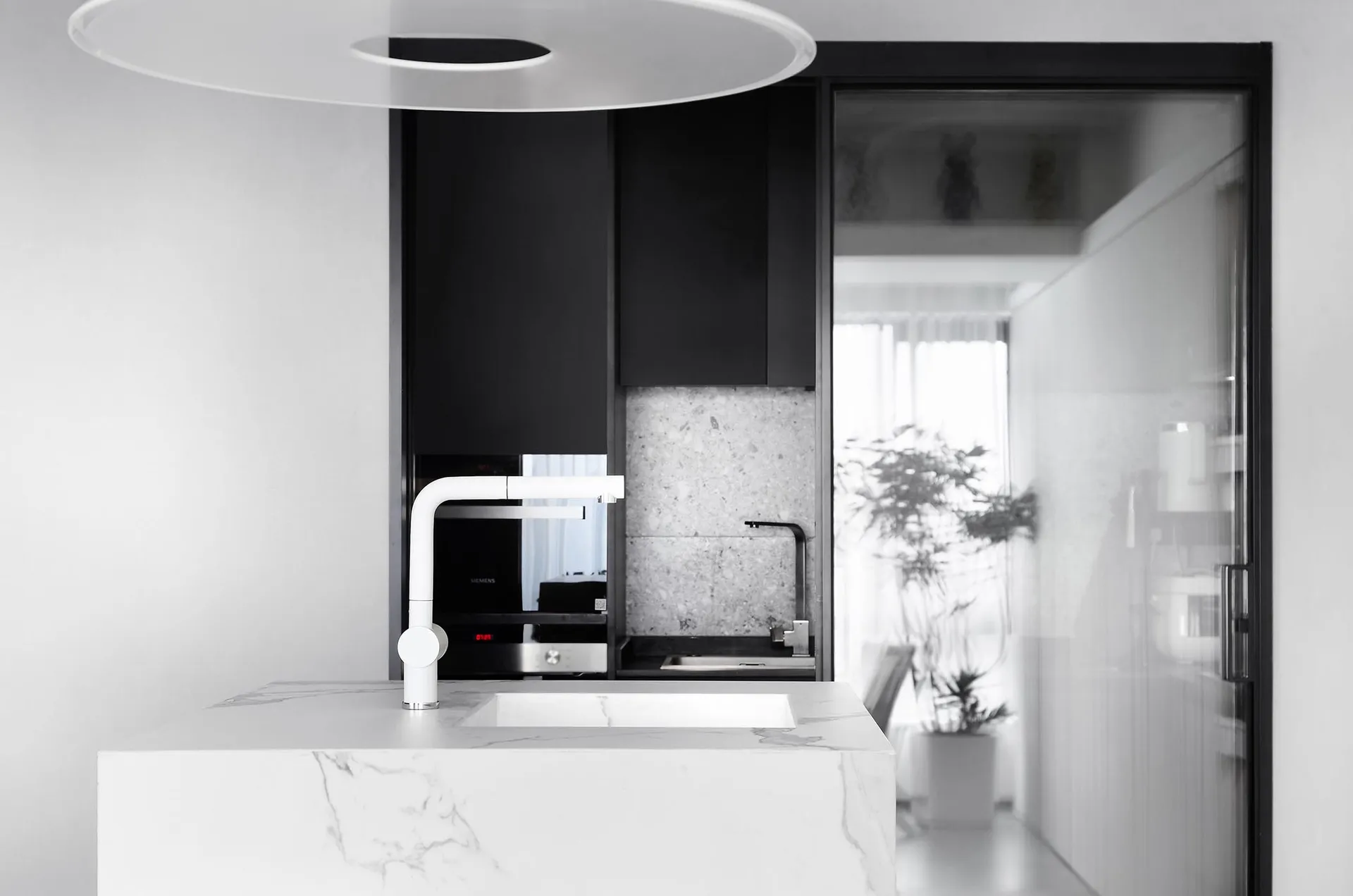 Modern kitchen with black cabinets, white marble countertops, and minimalist design