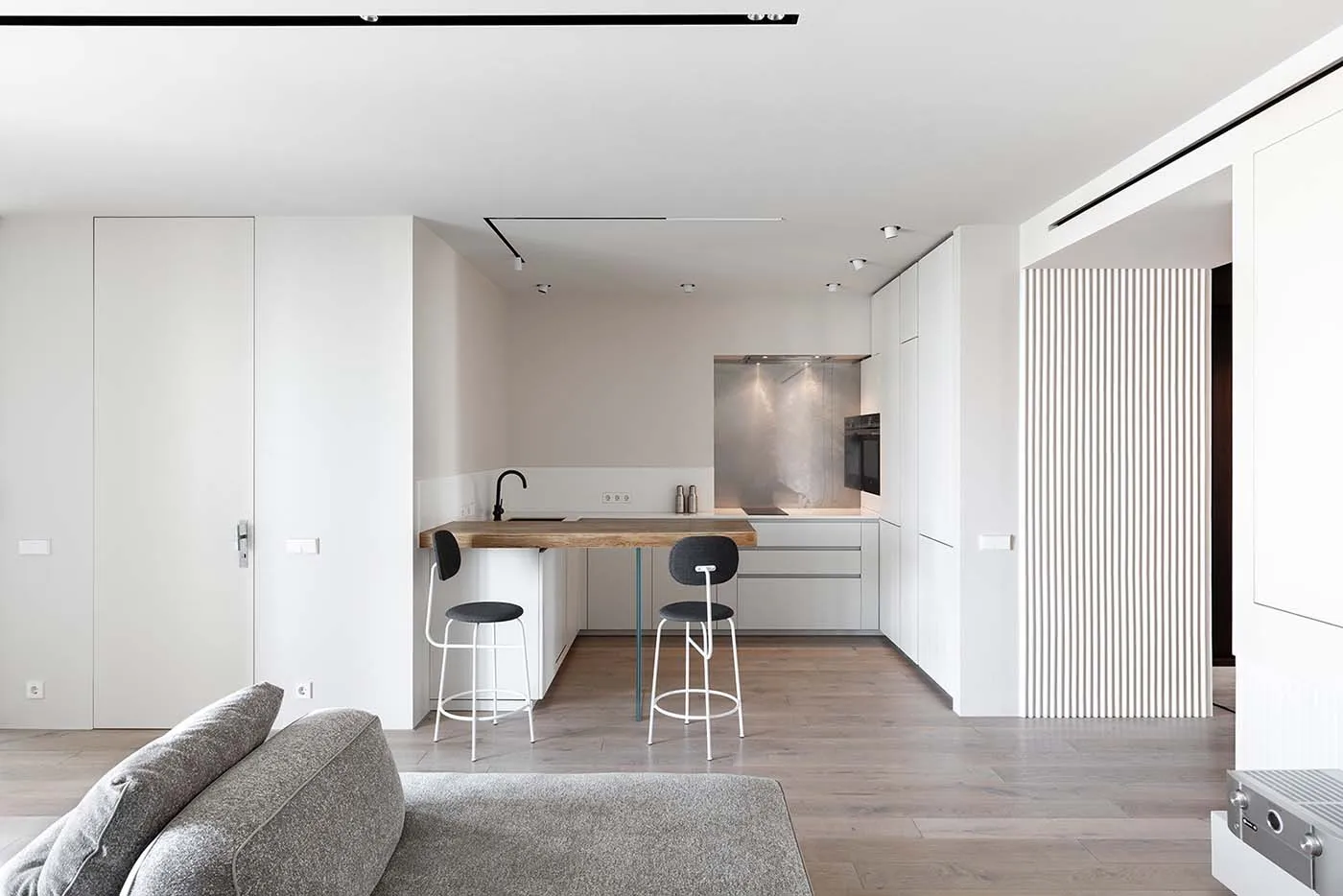 Modern minimalist kitchen with a wooden countertop and white appliances.