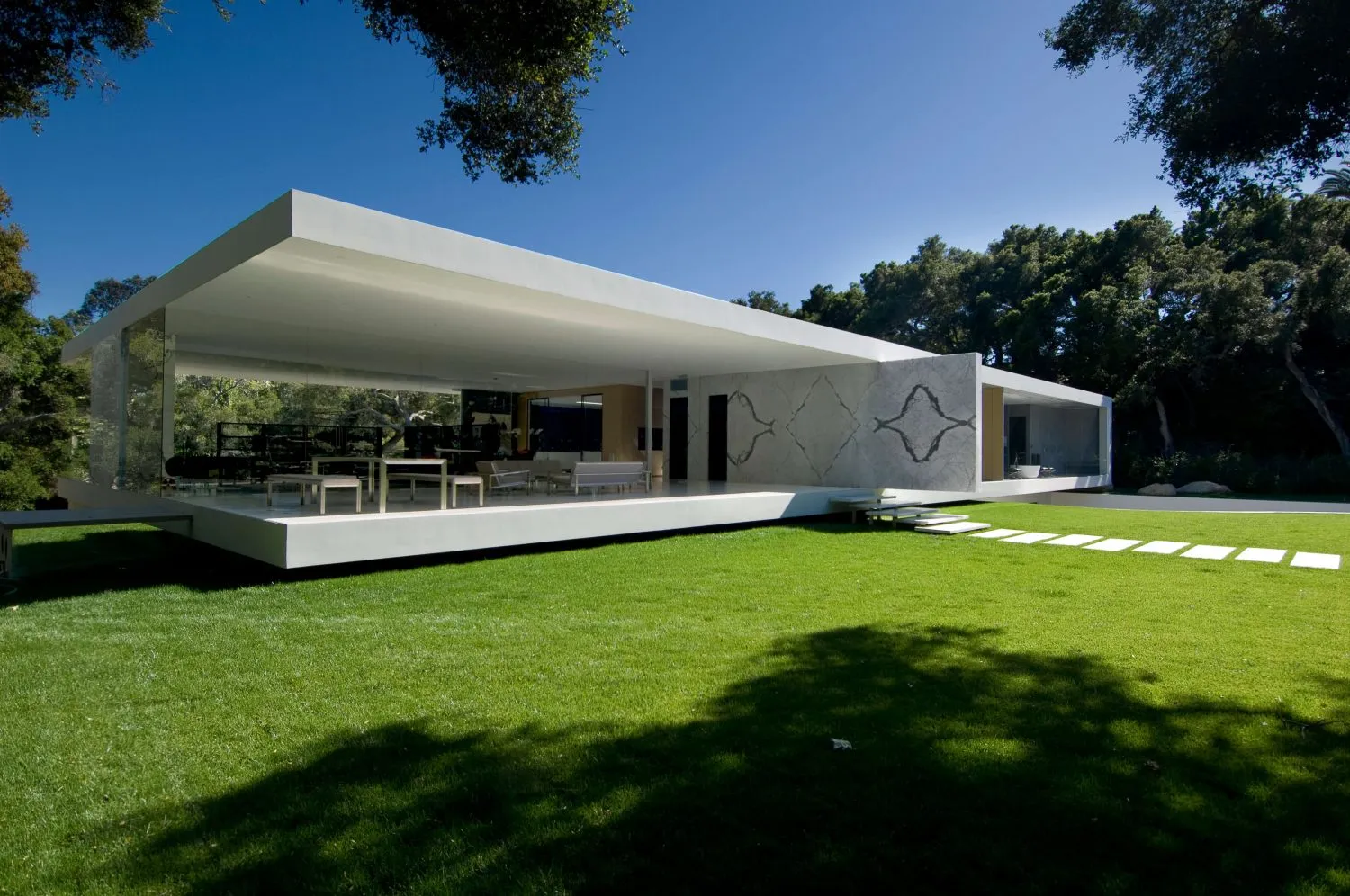 A modern residential exterior featuring glass and concrete materials.