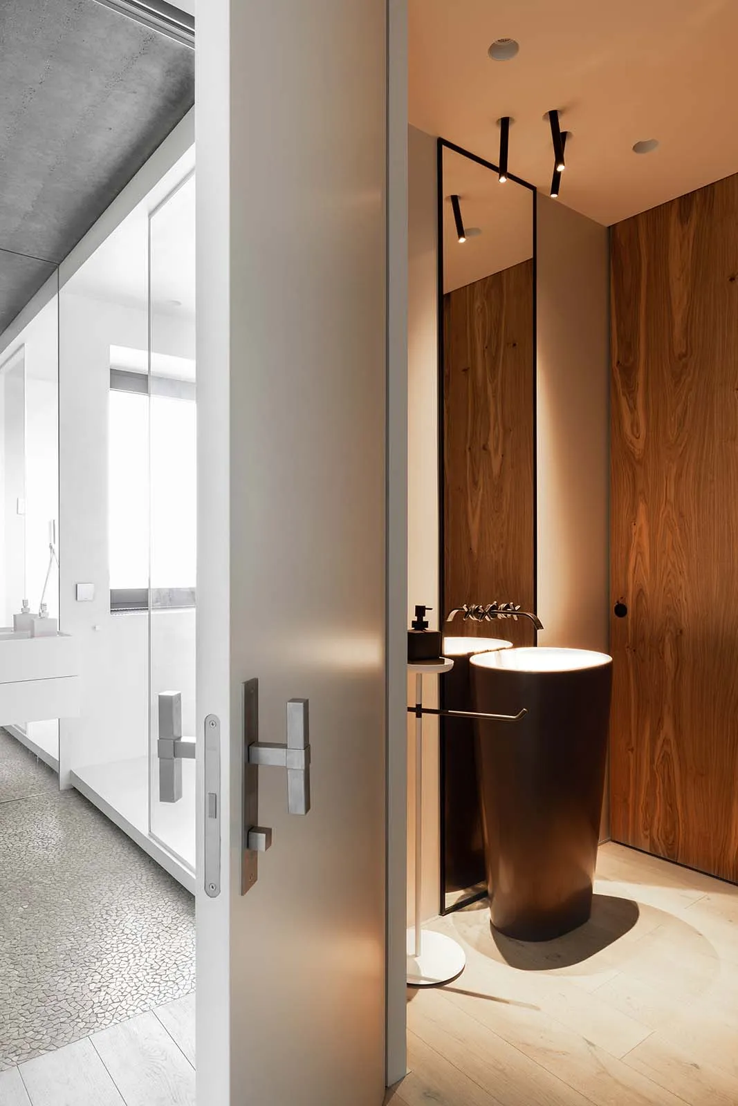 A modern bathroom featuring wood accents, light flooring, and metal fixtures.