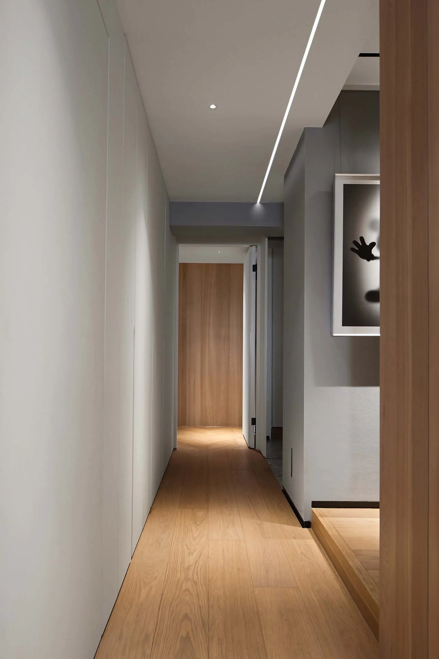 A minimalist hallway with wooden flooring and a light fixture.