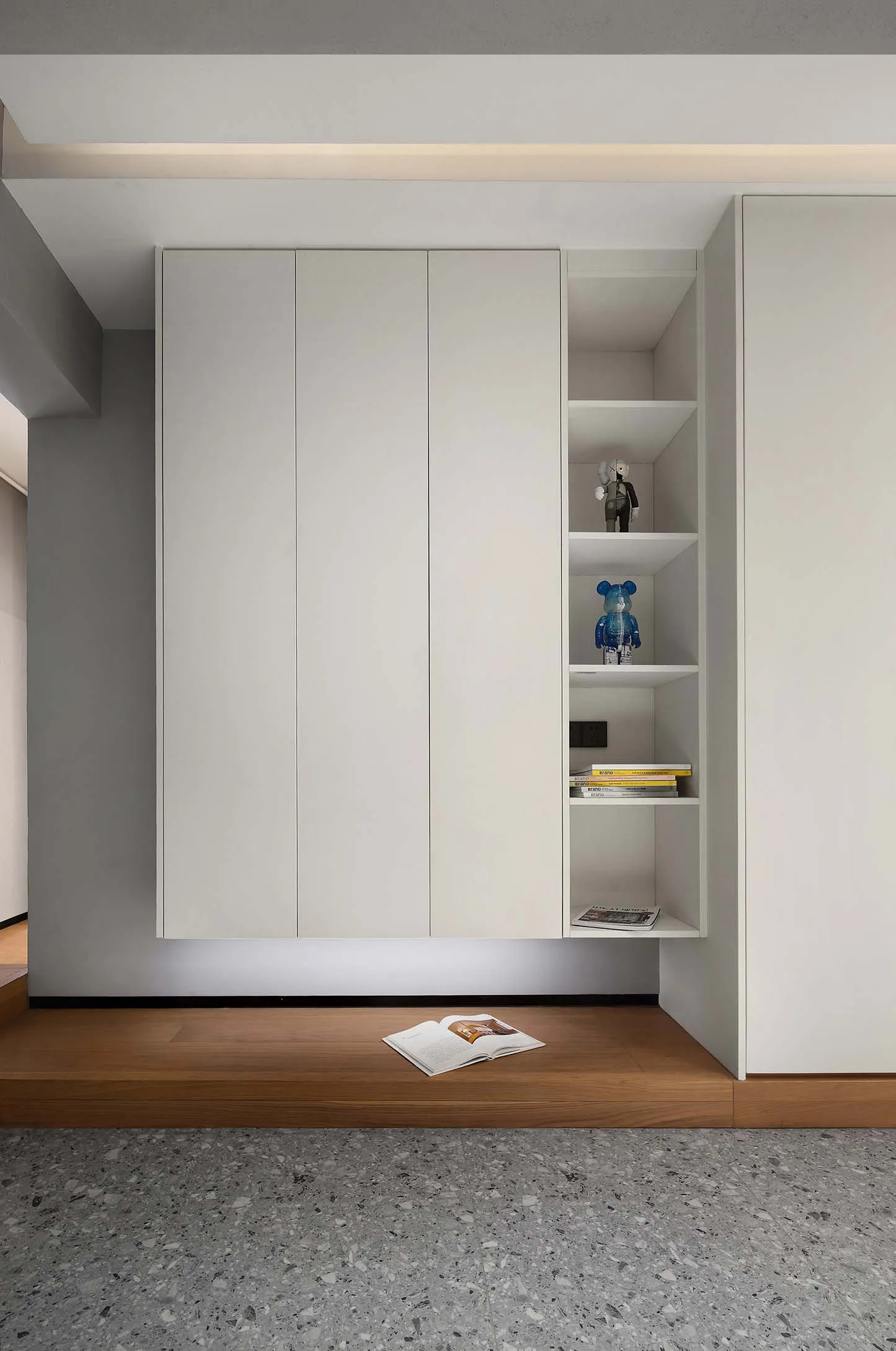 Modern minimalist storage shelves with white doors, featuring open shelving and decorative items on the right side.
