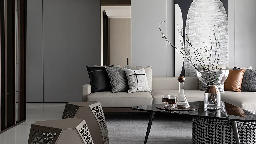 Modern living room with mixed materials, including a white sofa with patterned cushions, a glass coffee table, and geometrica