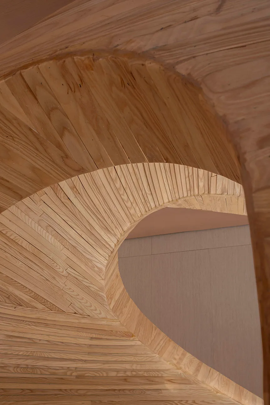 A minimalist wooden staircase with curved steps.