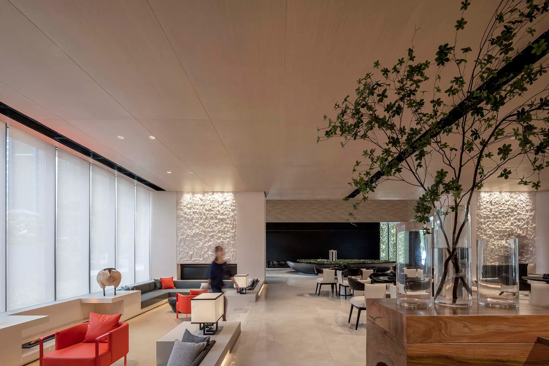 Modern hotel lobby featuring concrete and glass elements, with a minimalist aesthetic and contemporary furnishings.