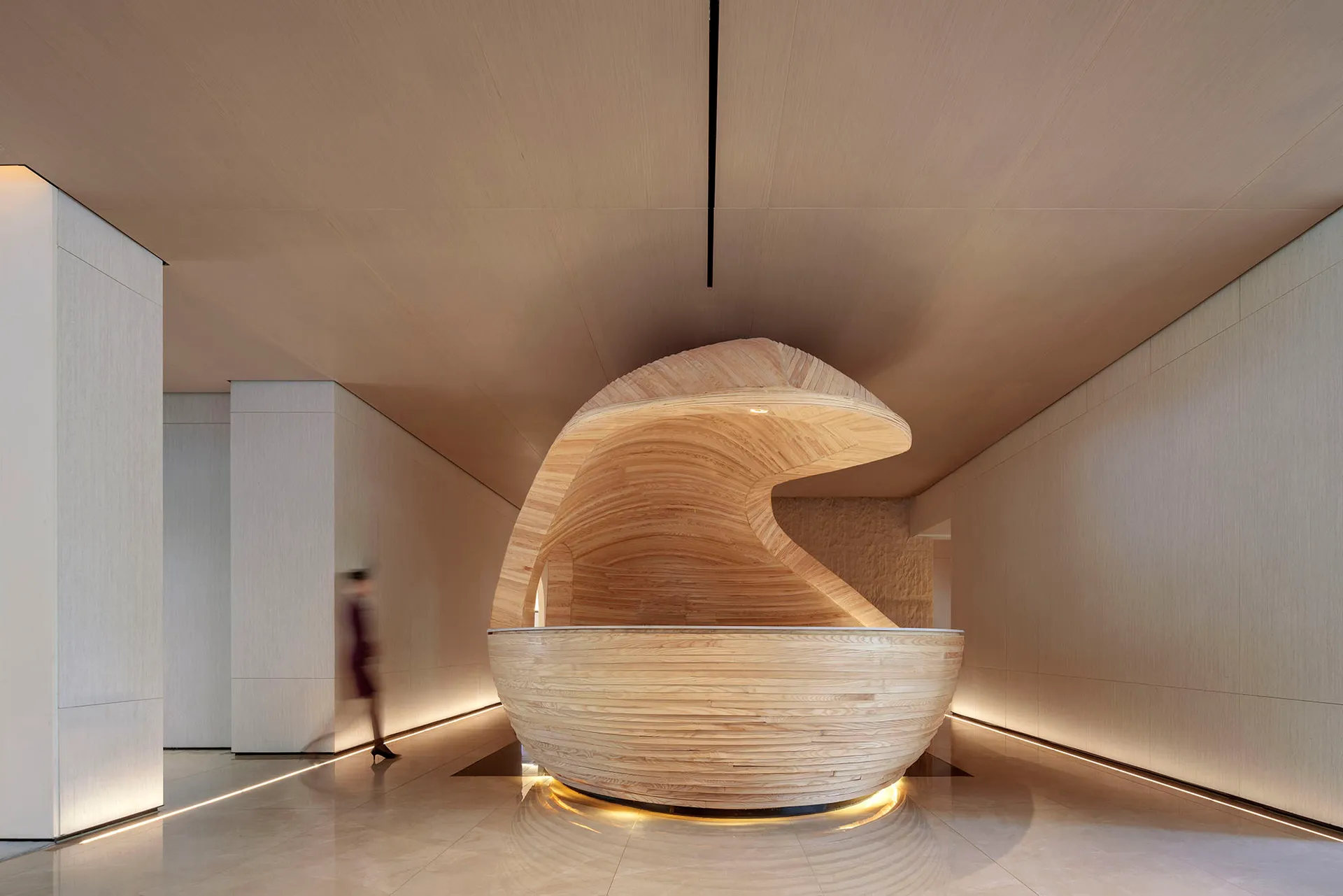 Modern lobby featuring a wave-shaped wooden reception desk.