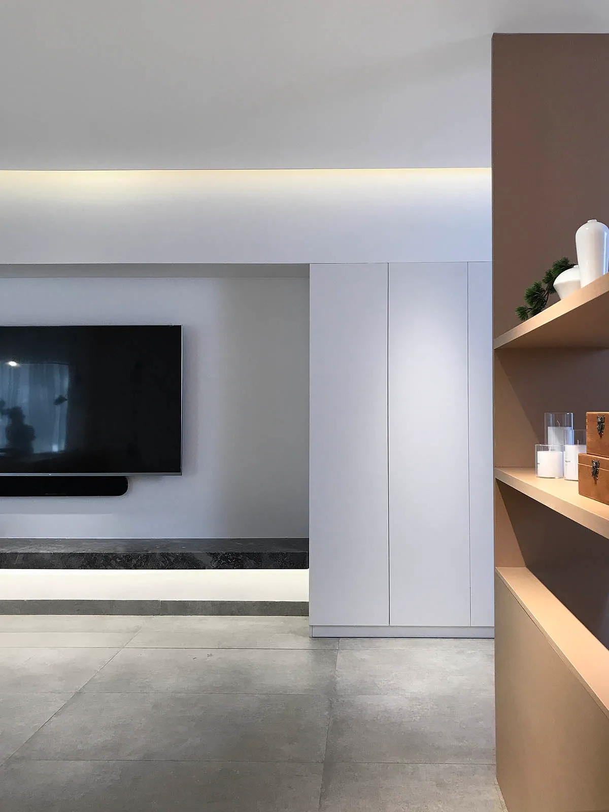 Modern minimalist living room with concrete floor, white storage cabinet, and sleek black TV unit.