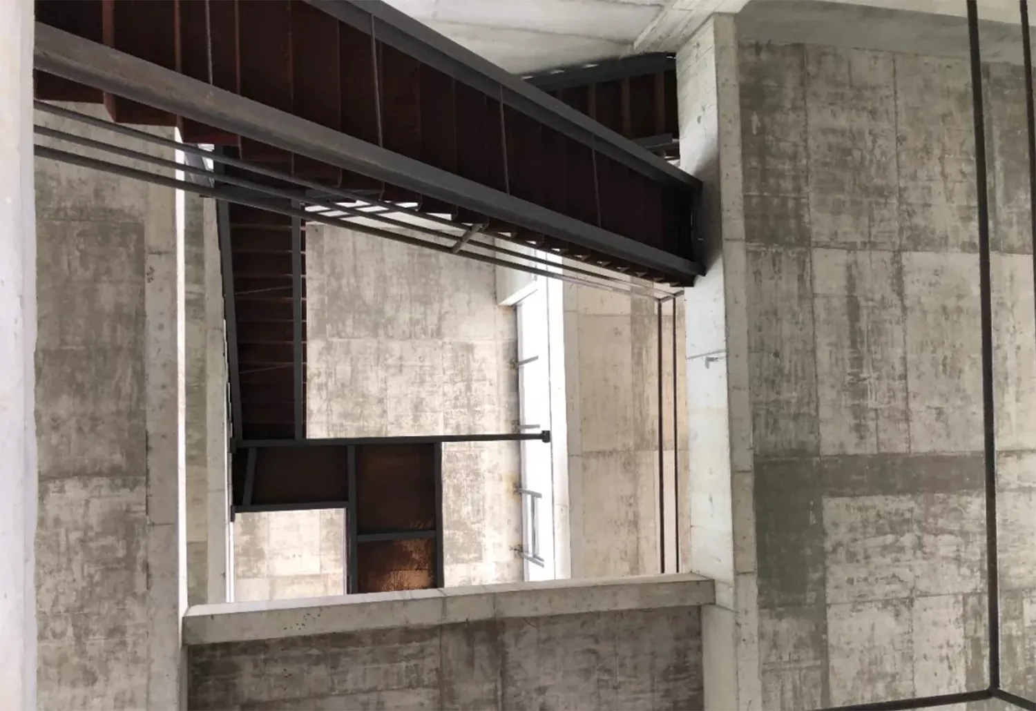 A modern concrete and steel staircase with a metal handrail.