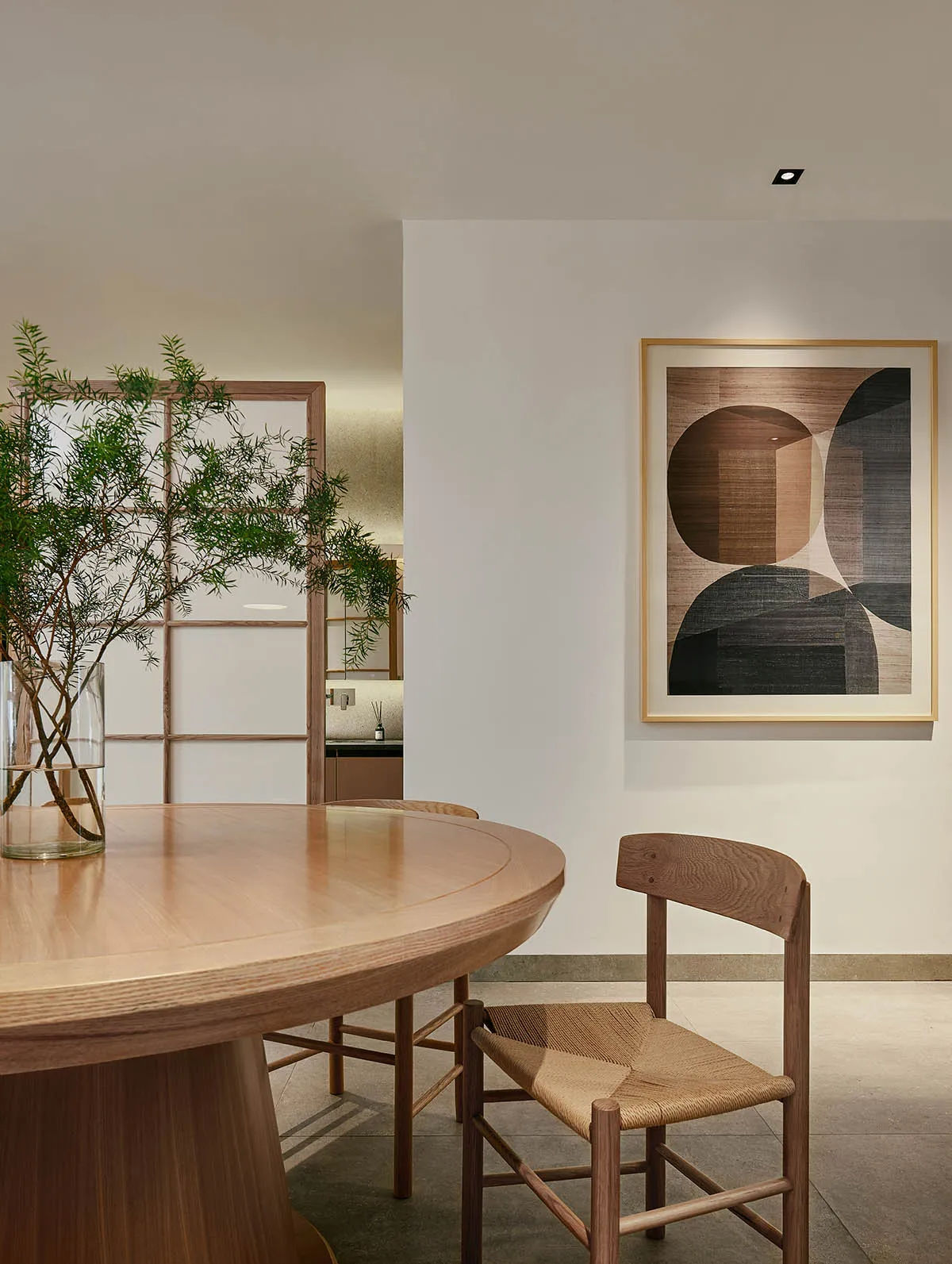 一間現代餐廳,內有木質餐桌、餐椅,以及插在花瓶裡的植栽。