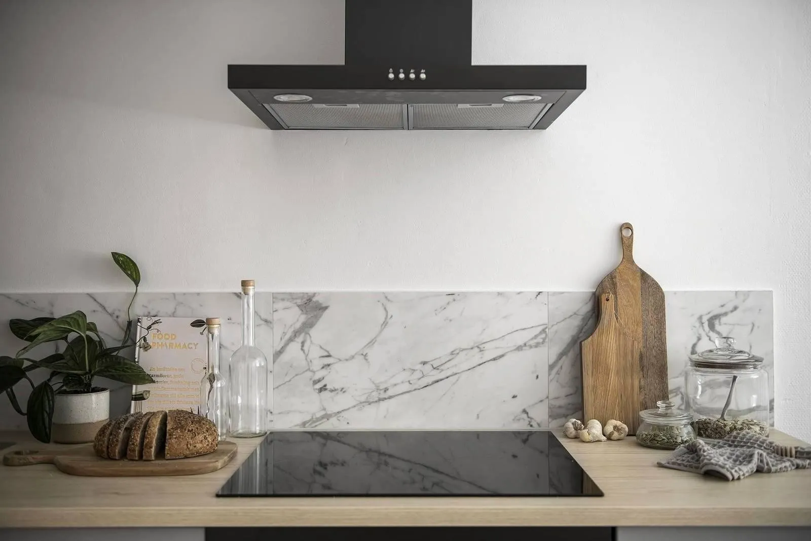 Modern minimalist kitchen with black stove top, wooden countertop, and marble backsplash