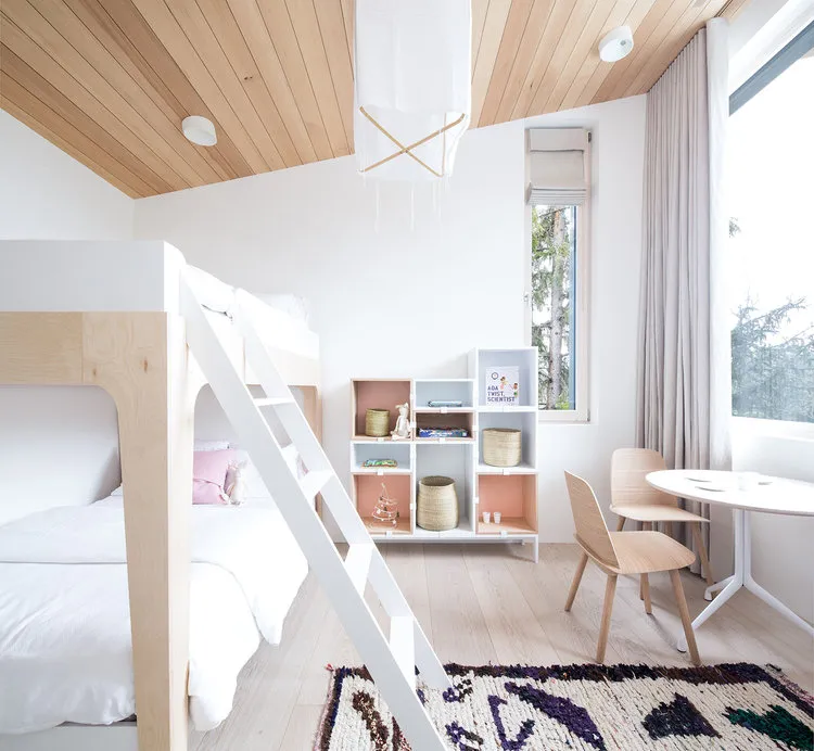 A minimalistic bedroom featuring a wooden bunk bed with a white ladder, a wooden chair, and a wooden bookshelf.