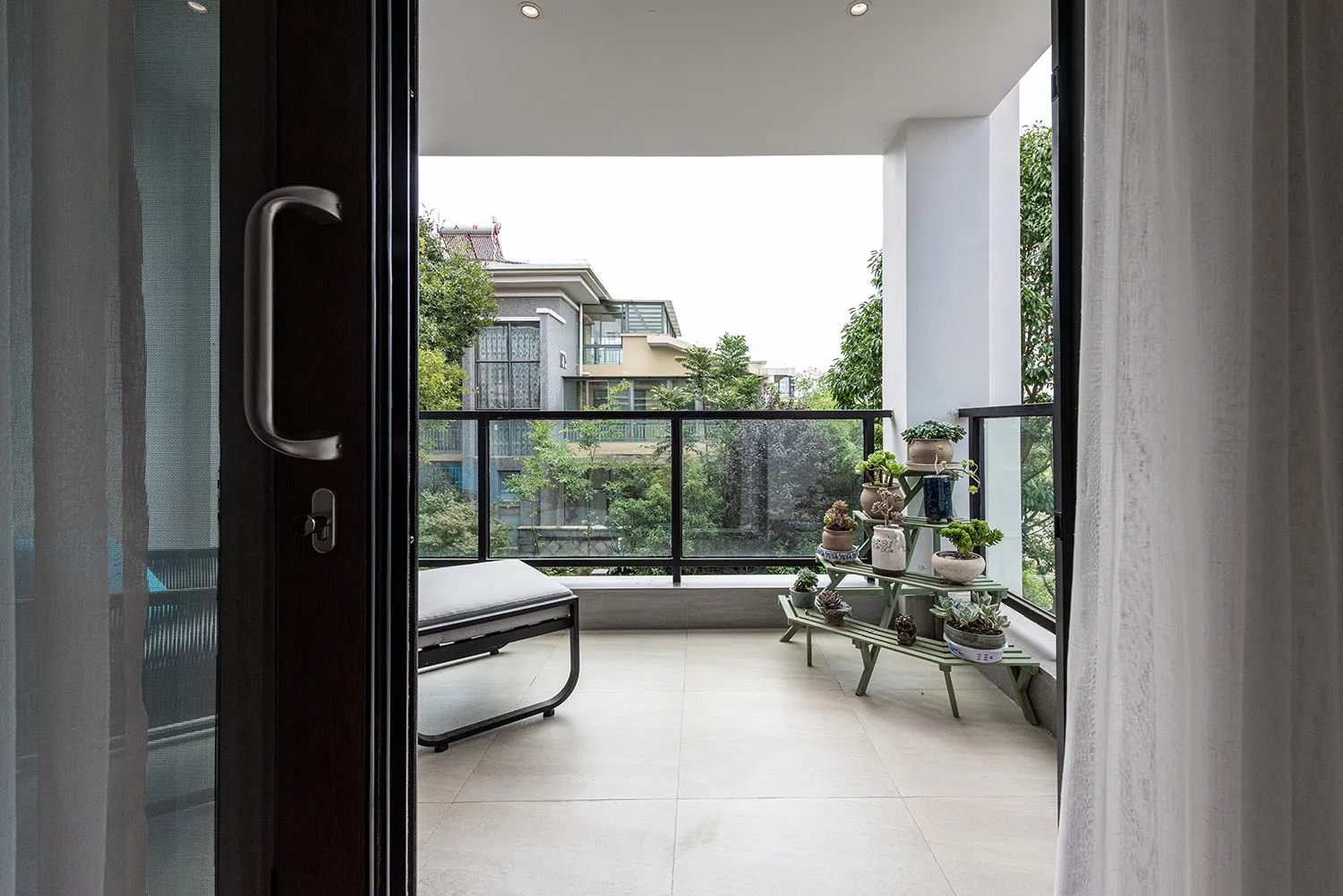 Modern balcony with floor tiles, glass railings, and wooden furniture