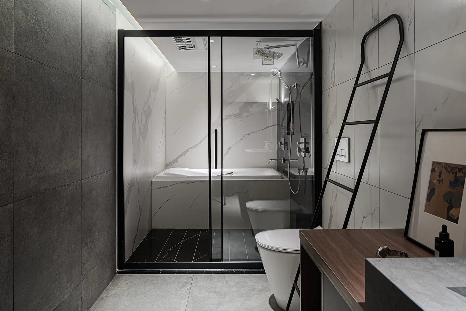 Modern bathroom with marble walls, glass shower enclosure, and split-level floor design.