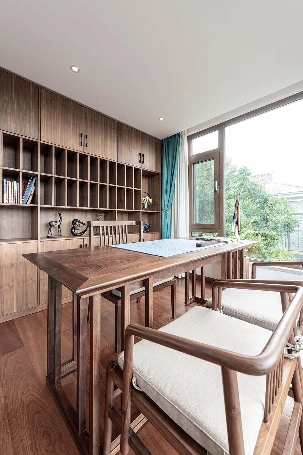 A modern home office featuring wooden furniture and a large window.
