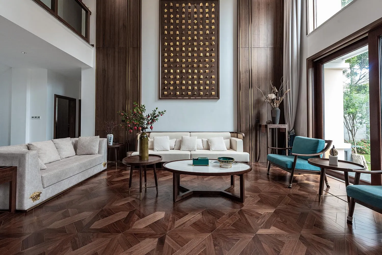 Modern living room with white sofas, blue armchairs, and a coffee table on wooden flooring.