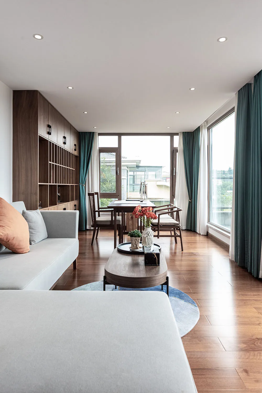 Modern living room furniture with wooden accents and glass walls, featuring a comfortable seating area and a dining table.