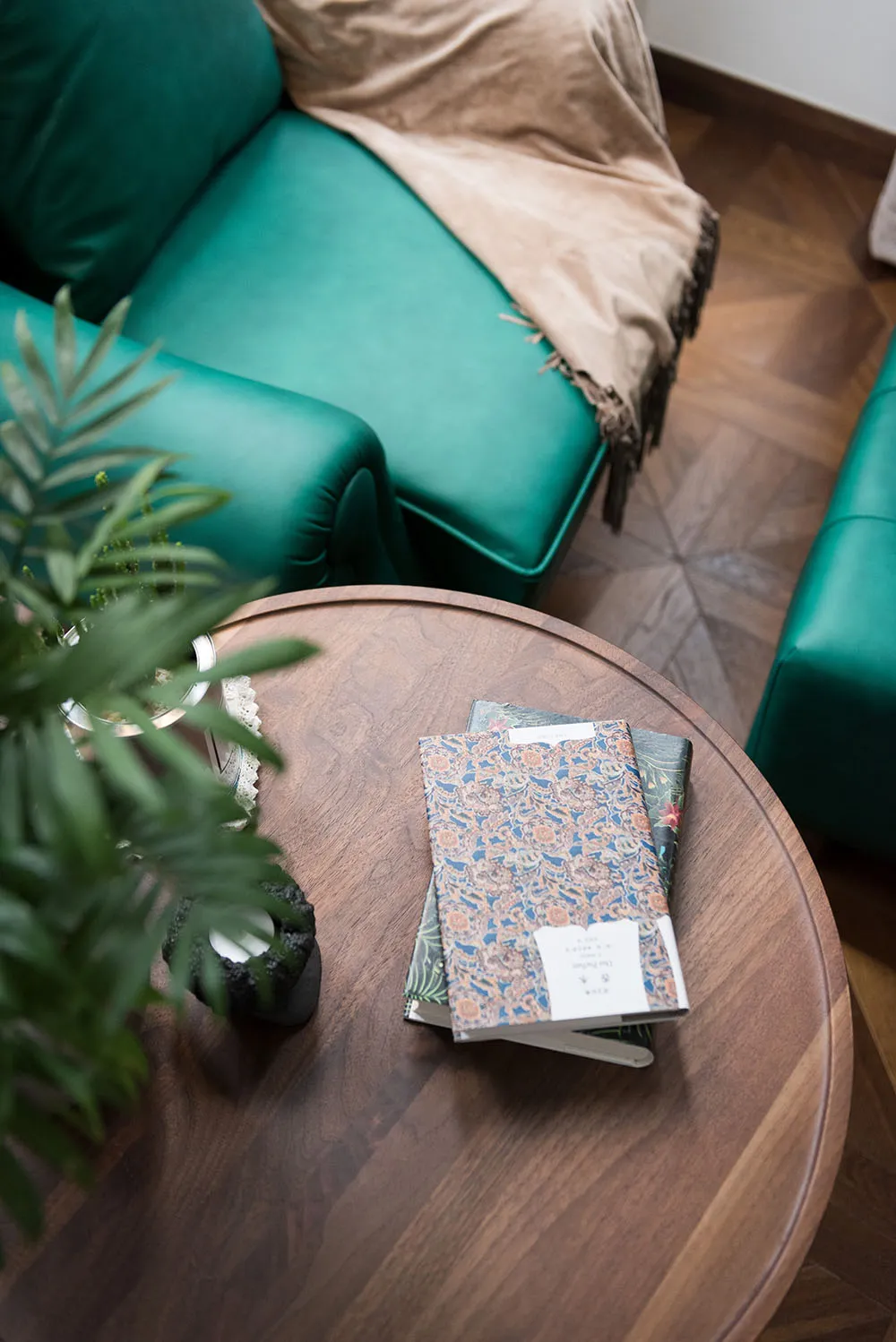 A modern green sofa with a beige throw blanket in a living room setting.