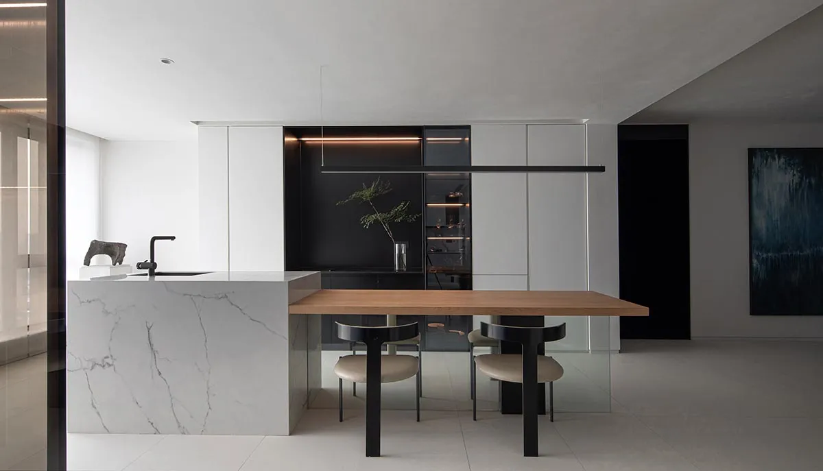 Modern minimalist kitchen with marble countertop and black cabinets.