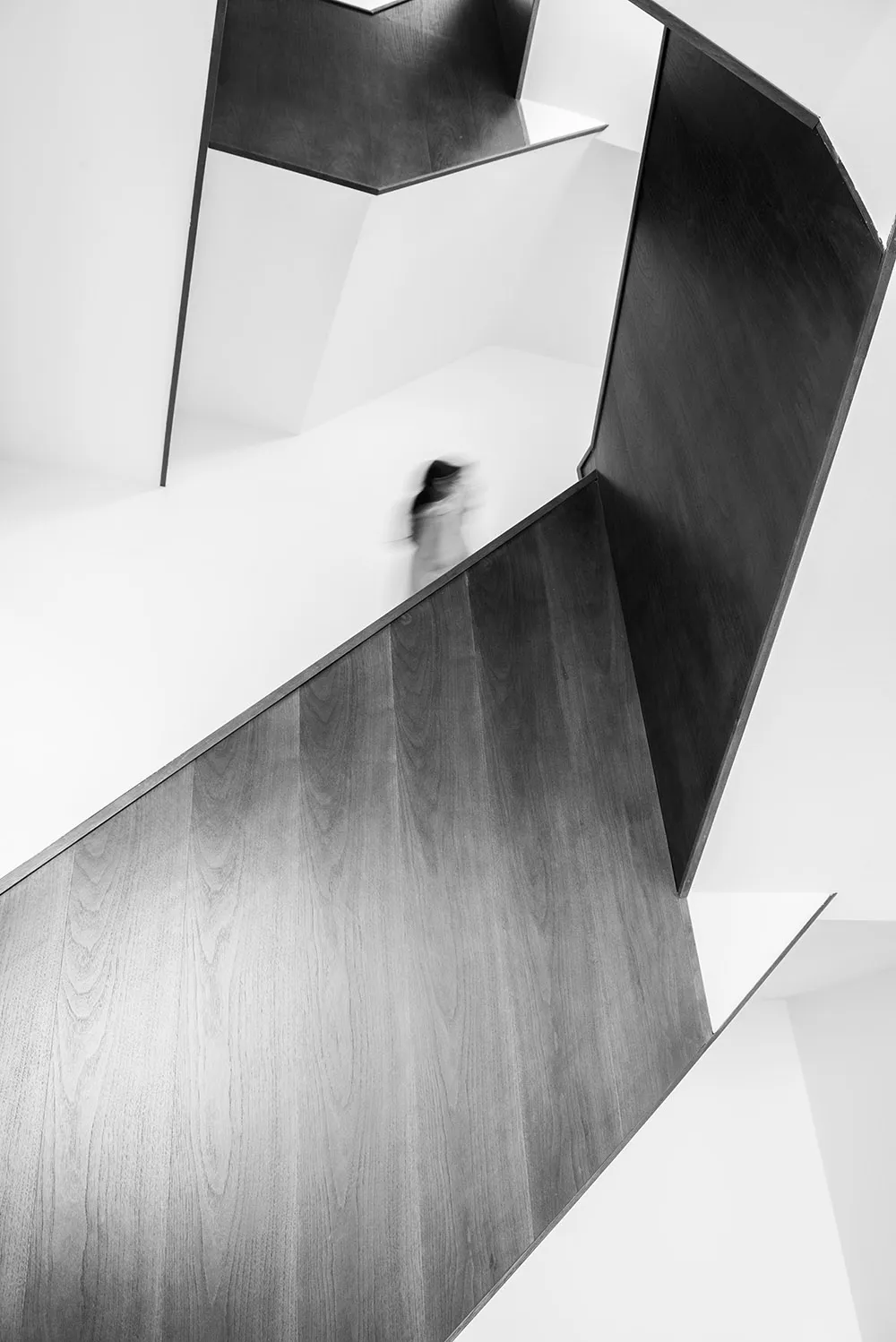 A modern interior with a grey scaling staircase made of wood and glass.