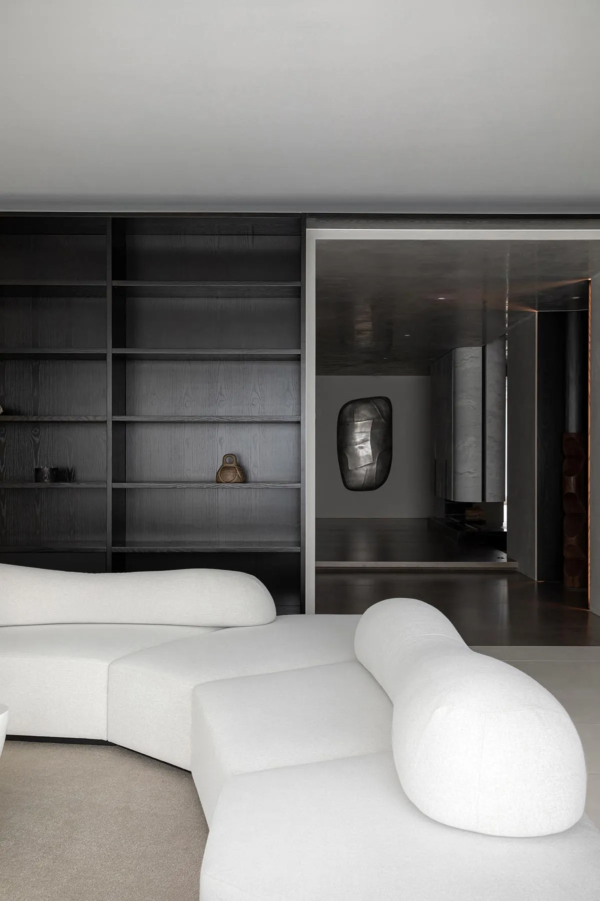 Modern living room featuring a white, curved sofa and black bookshelf.