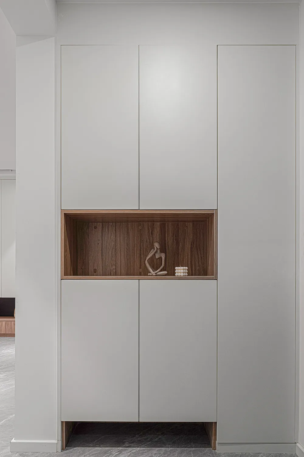 A modern metal cabinet with a wooden shelf featuring a sculpture and small candles.