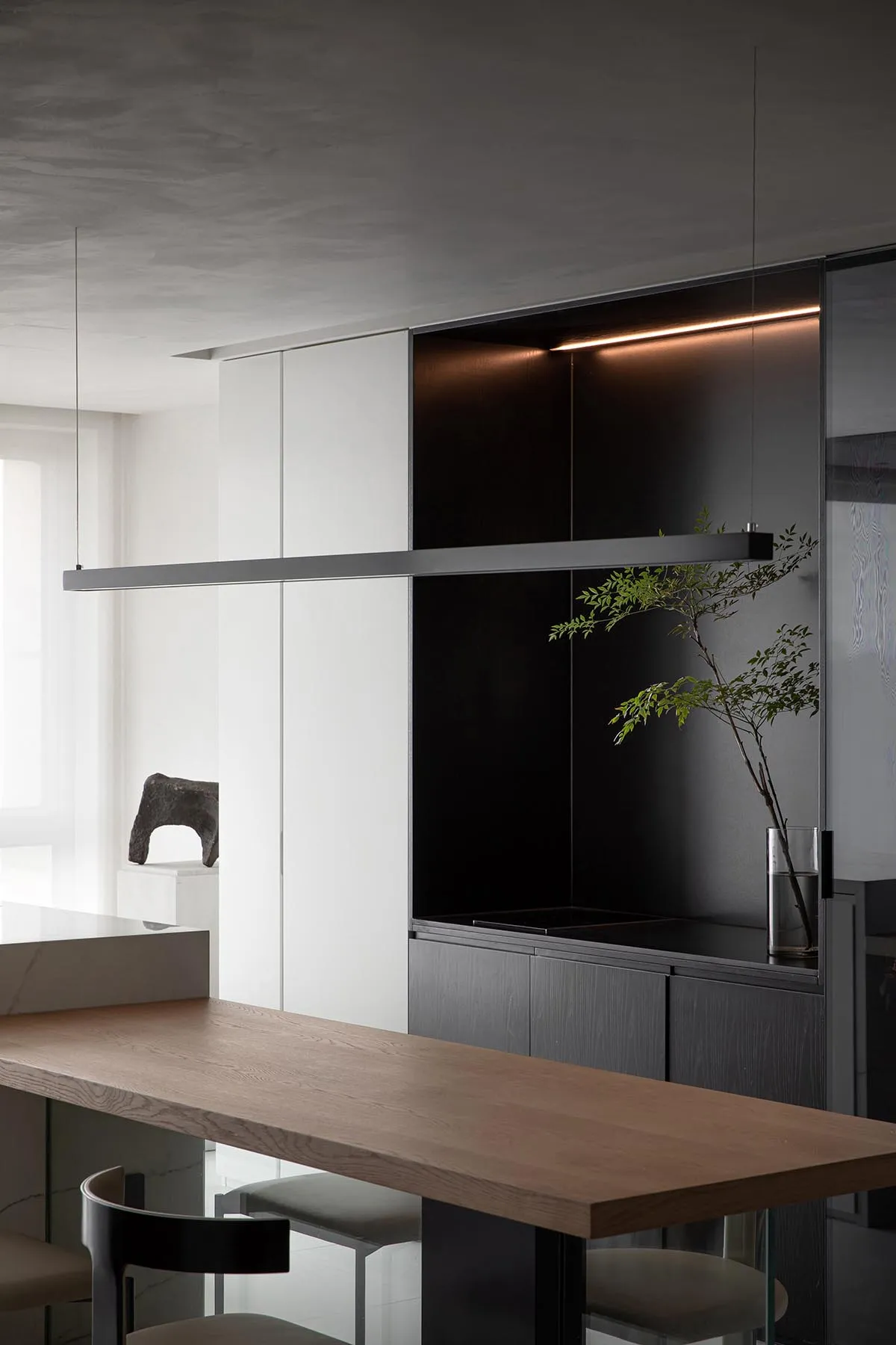 A modern minimalist kitchen featuring wooden countertops, metal accents, and glass cabinets.