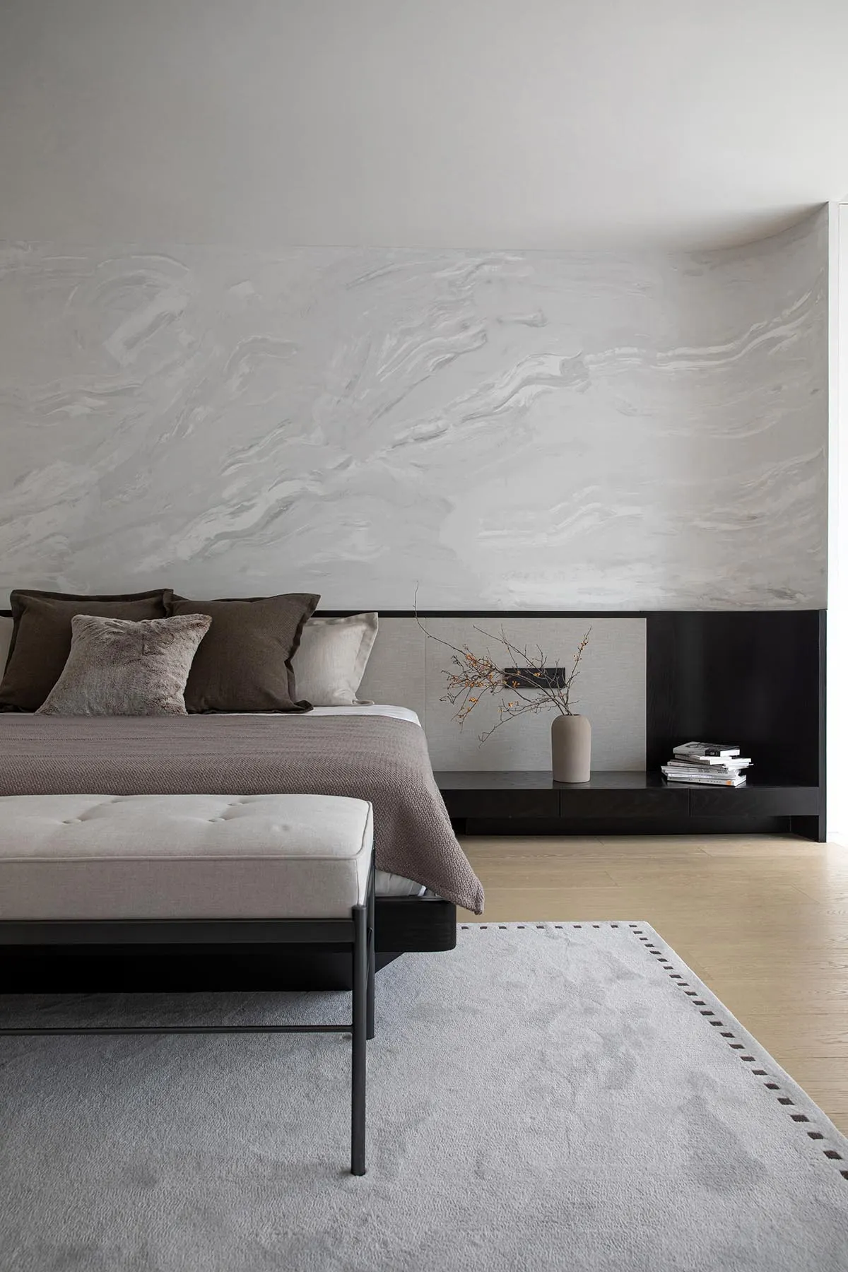 A modern bedroom with neutral-toned walls, bedding, and furniture, featuring a minimalist design style.