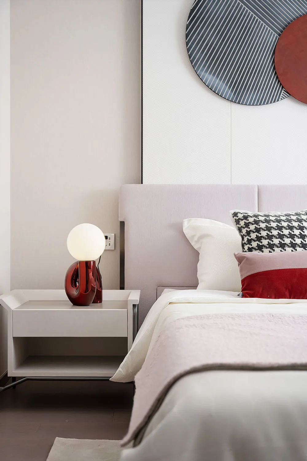 Modern minimalist bedroom featuring a bed with a soft fabric headboard, wooden floor, and a metallic bedside lamp.