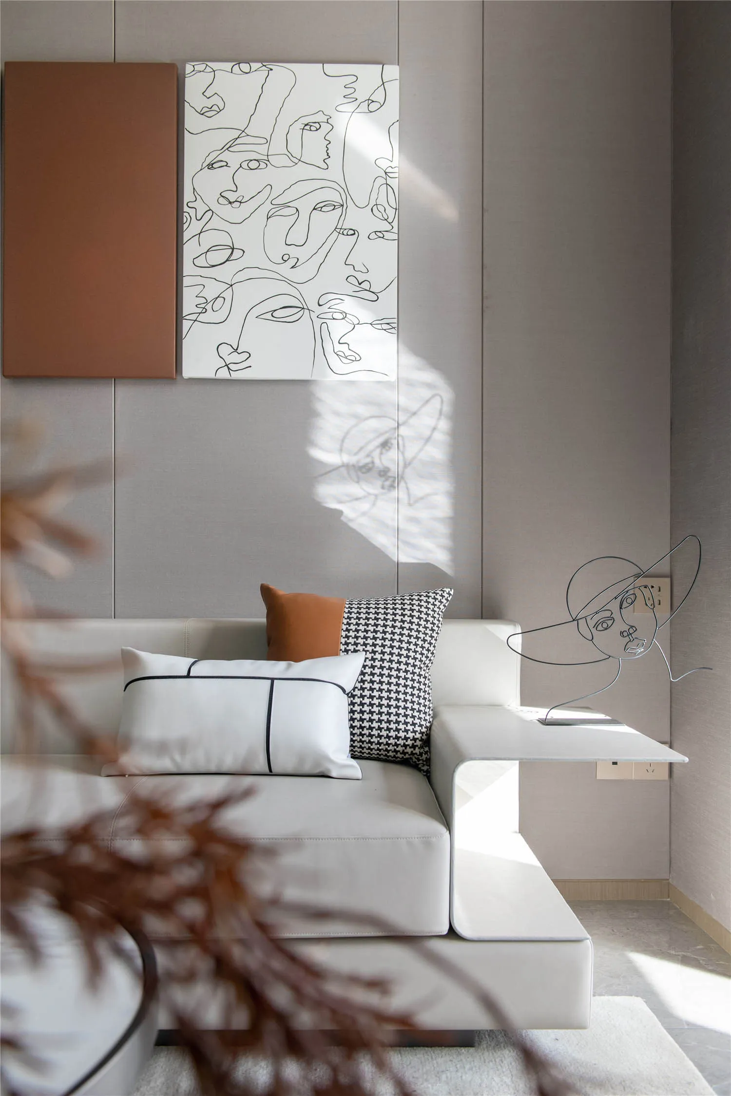 Minimalist living room with white leather sectional sofa, abstract art on the wall, and metallic sculpture on the side table.