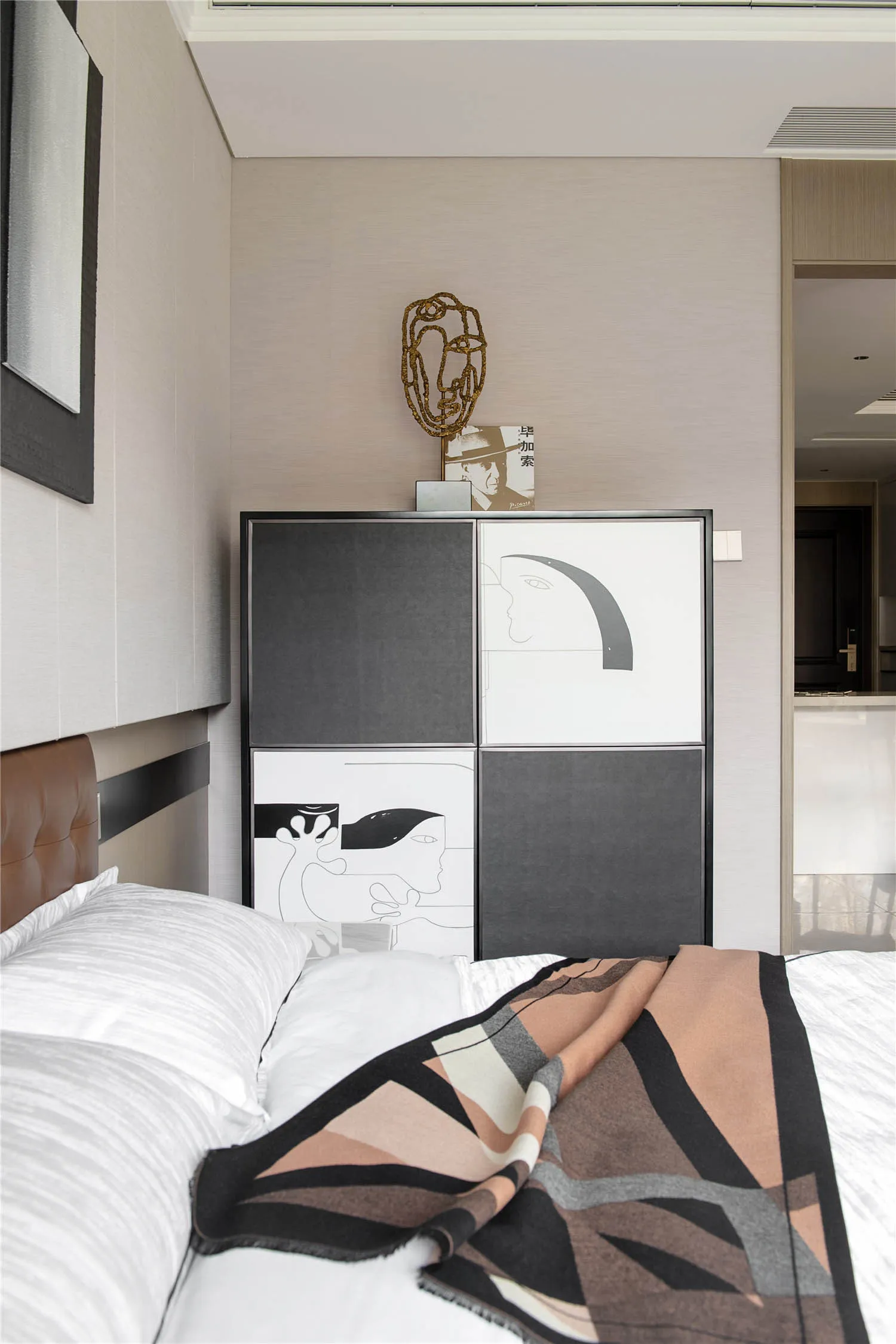 A modern bedroom featuring fabric bedding and abstract artwork.