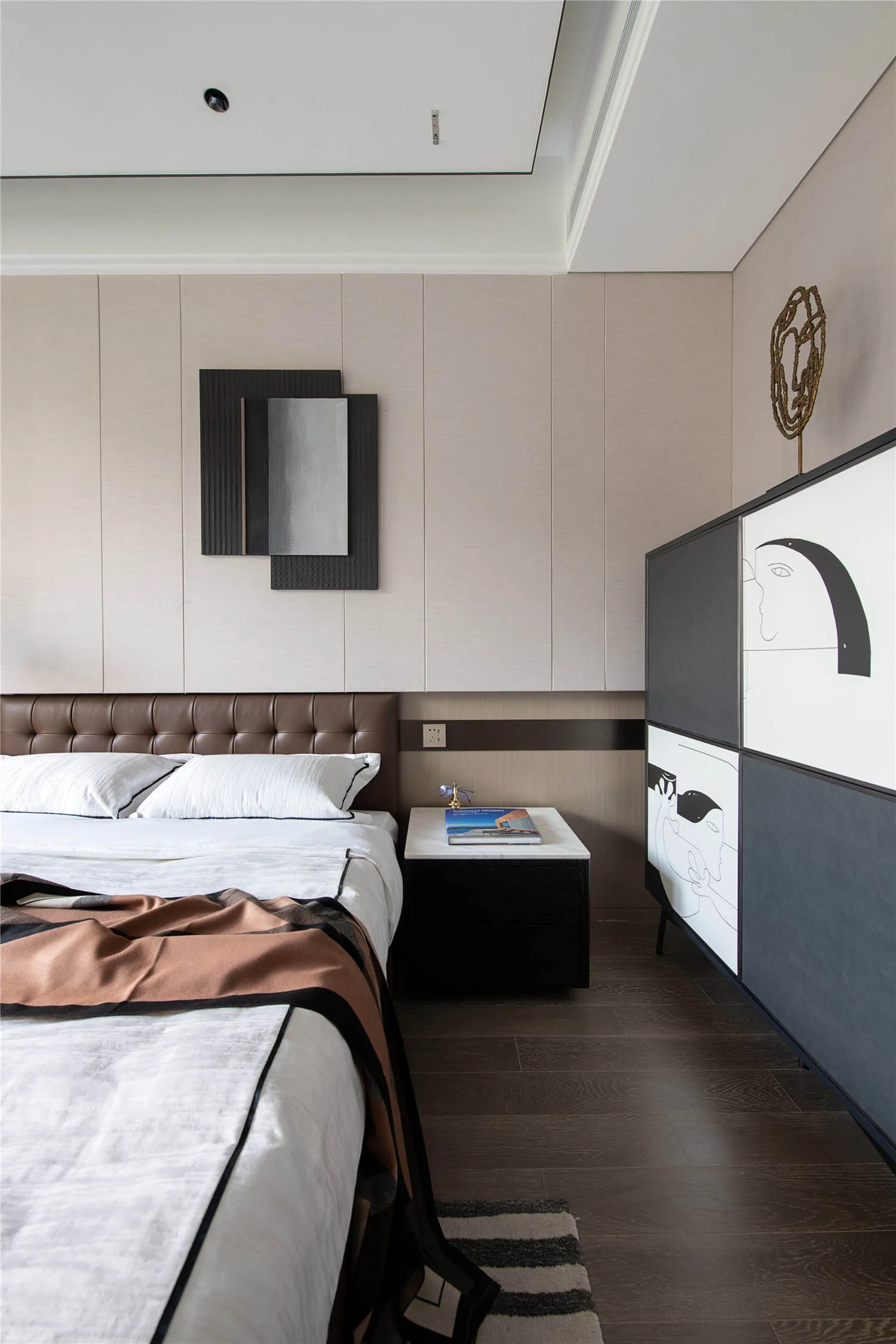 Modern bedroom featuring wooden flooring and fabric bedspread, with minimalist decor and a minimalist side table.