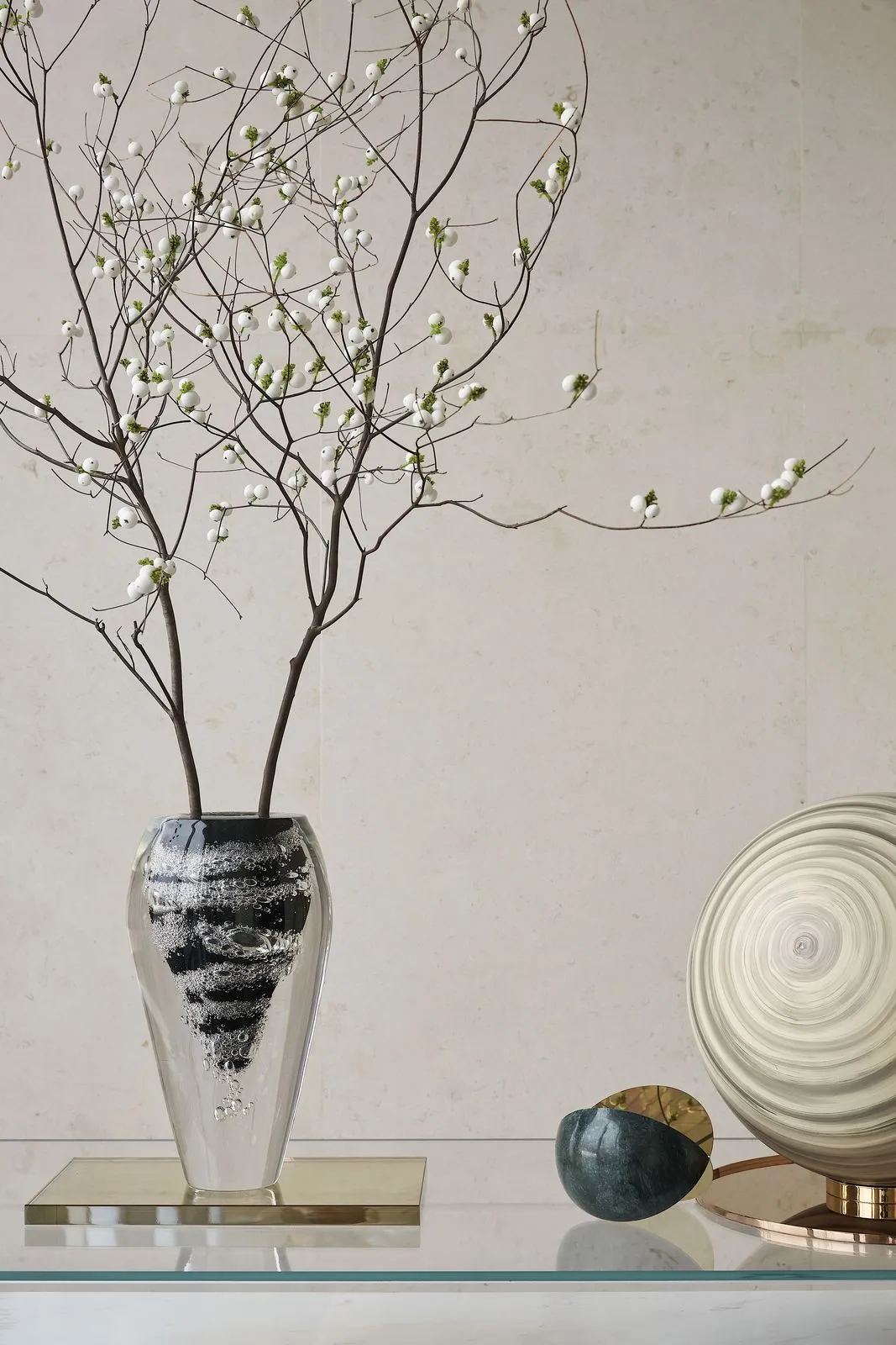 Modern decorative glass vase adorned with delicate white berries on a sleek surface.