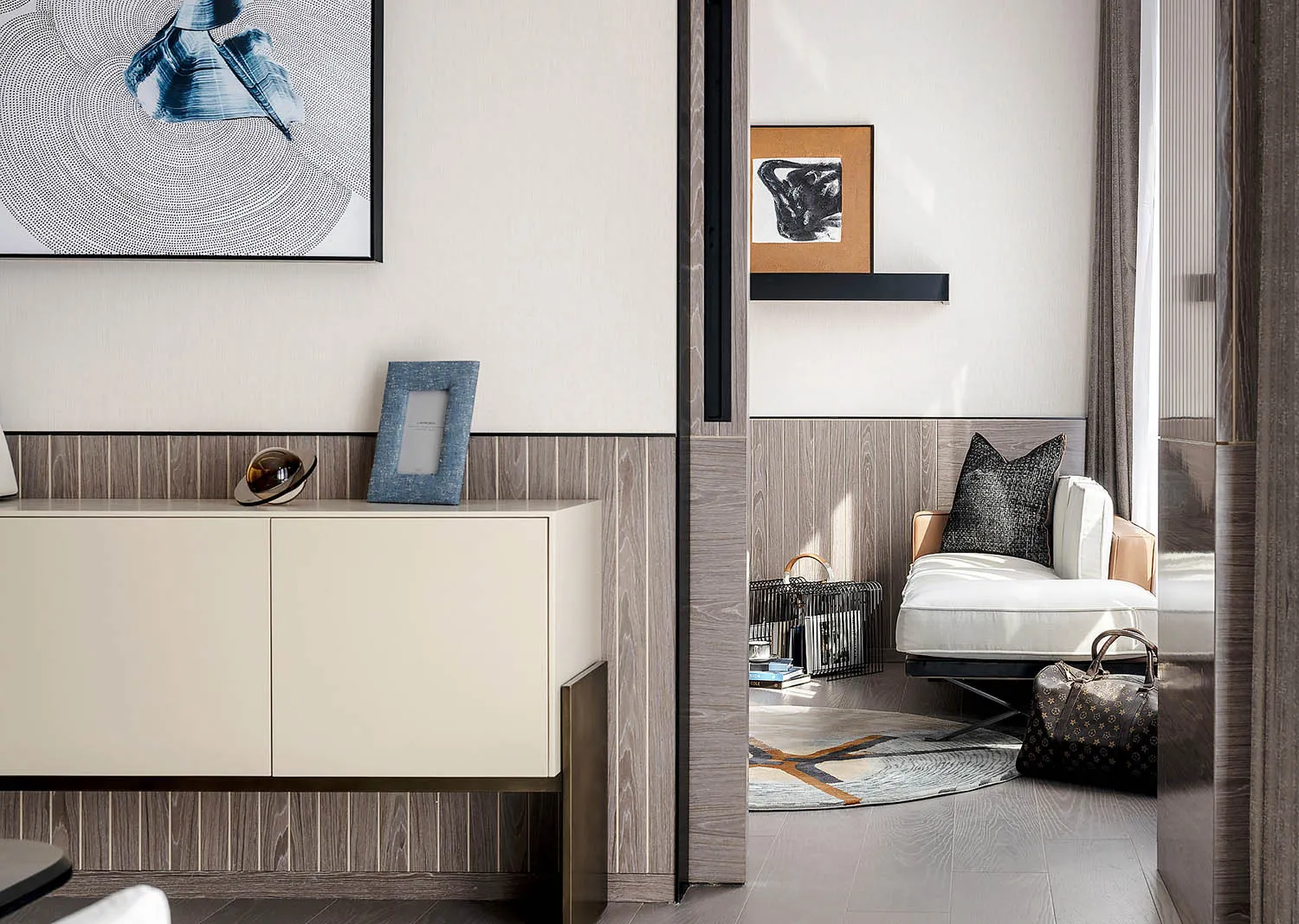 Modern living room featuring wood-paneled walls and a white upholstered chair with a black and white abstract painting hangin