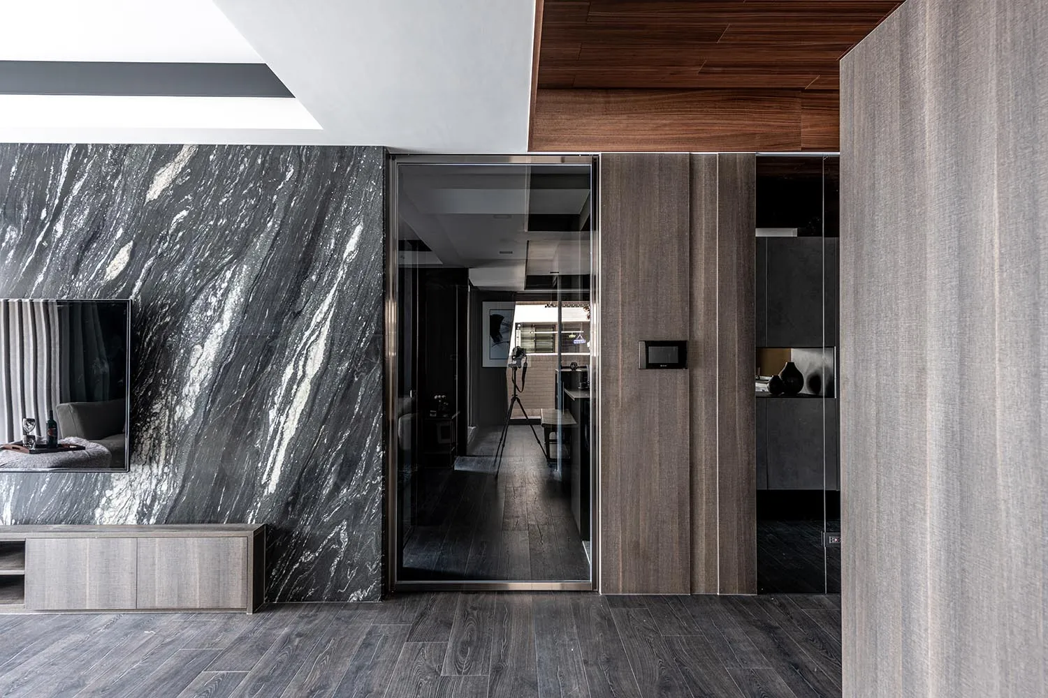 A modern living room with a marble accent wall and concrete flooring.