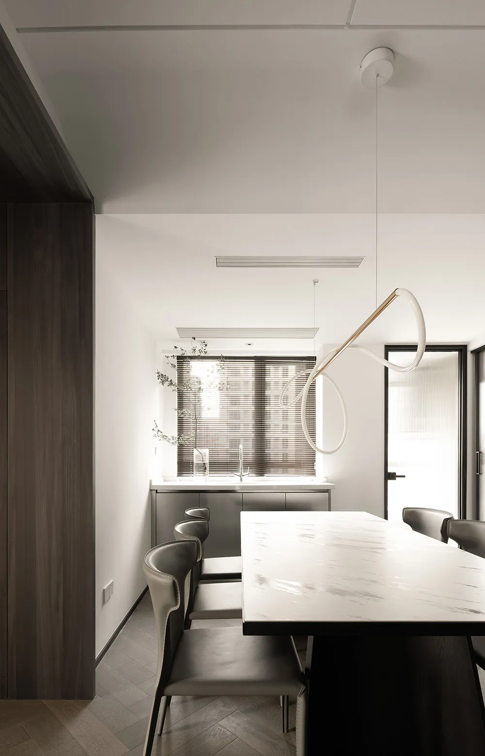 Modern dining room featuring a white marble dining table and minimalist design with dark wooden accents and a Hanging Light F