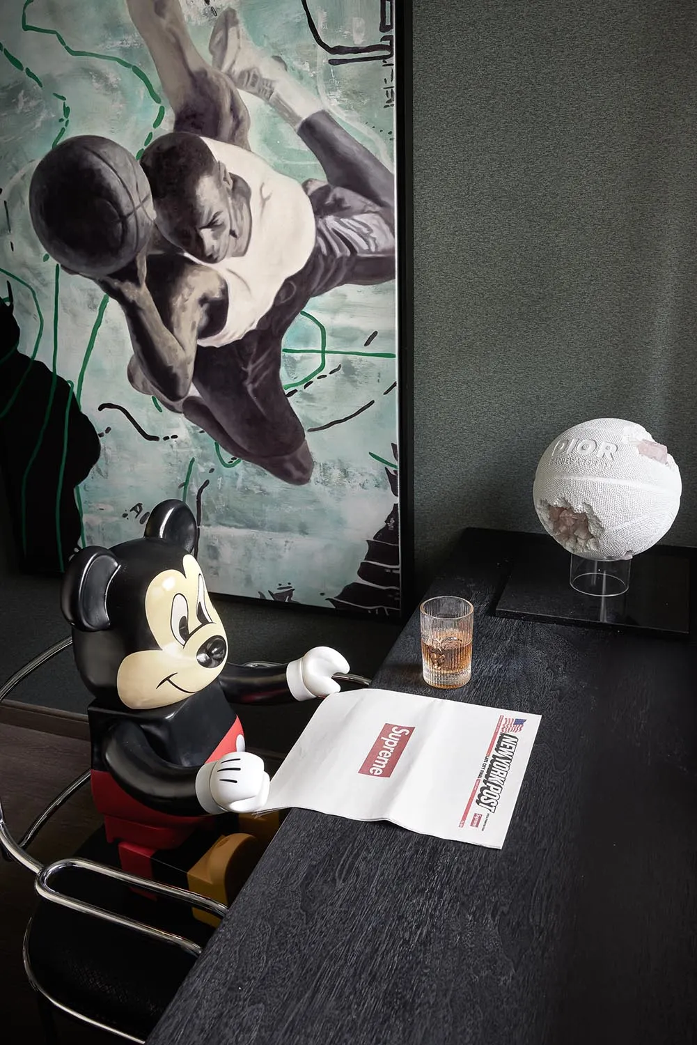 A modern minimalist interior featuring a black and white theme with a Mickey Mouse figurine holding a newspaper, a basketball