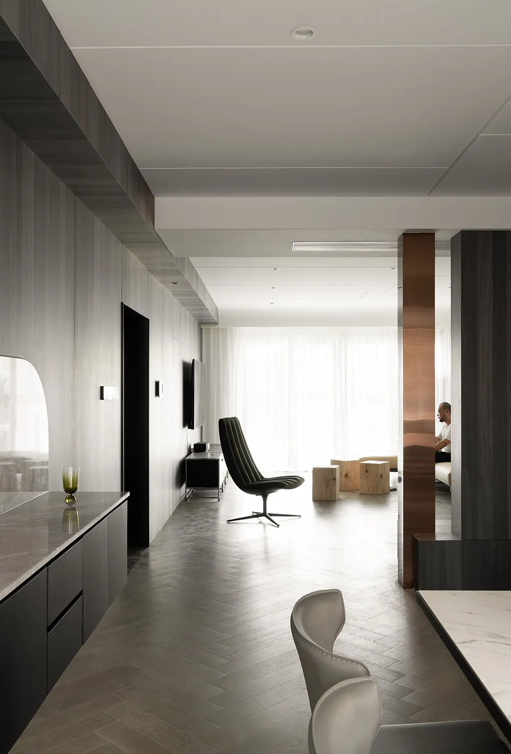 Modern residential interior with a mix of natural wood texture, white marble flooring, and a sleek black TV screen.