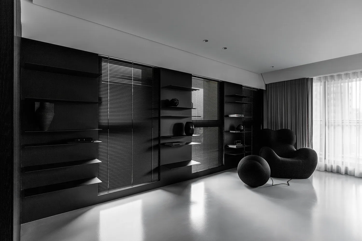 A minimalist residential interior featuring black metal furniture and glass elements.