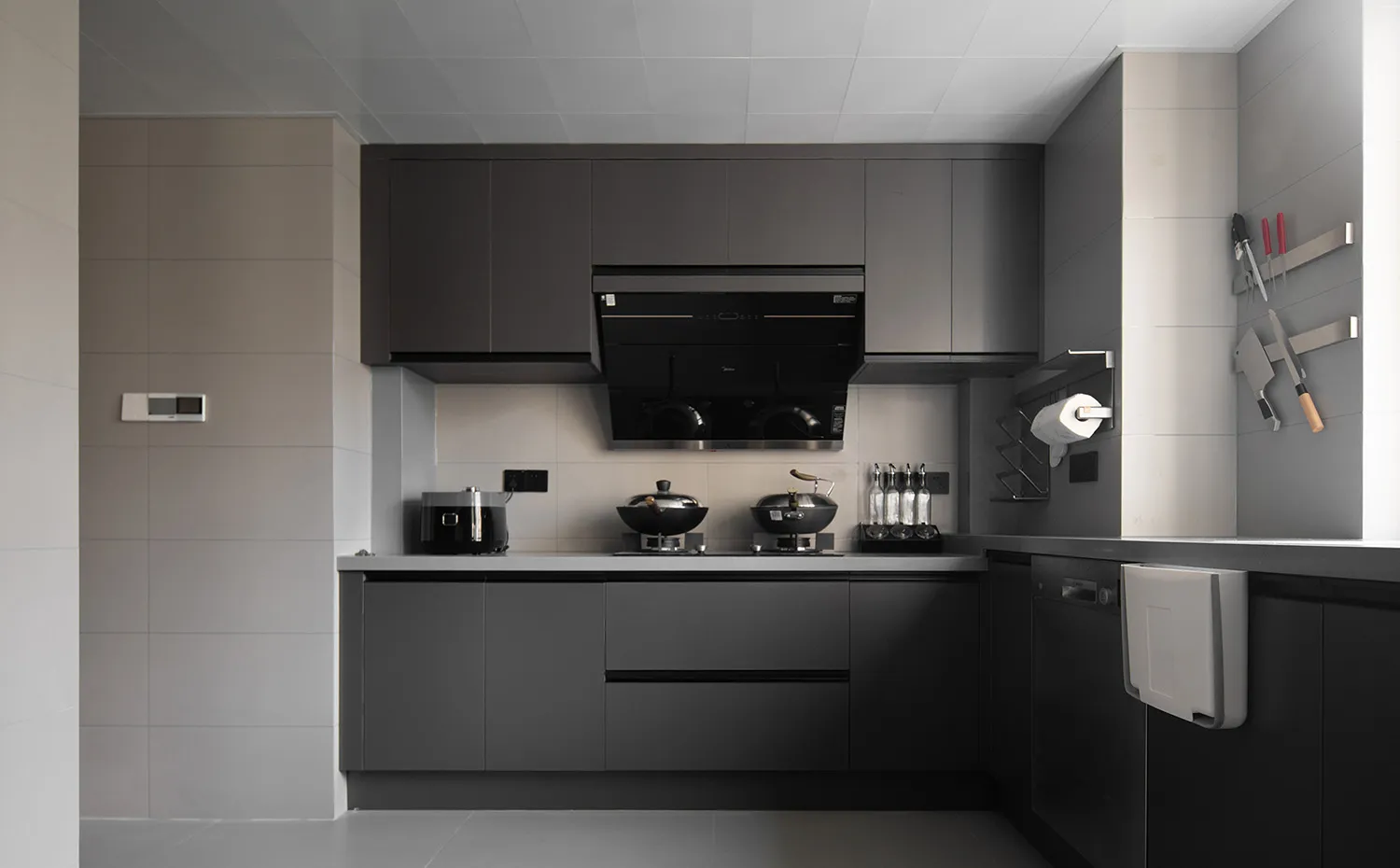 A modern black kitchen with concrete countertops and minimalist design elements.