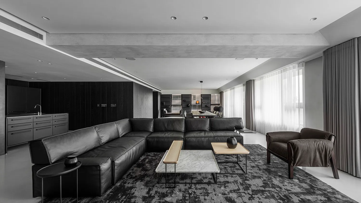 A modern living room featuring black leather furniture and minimalist decor.
