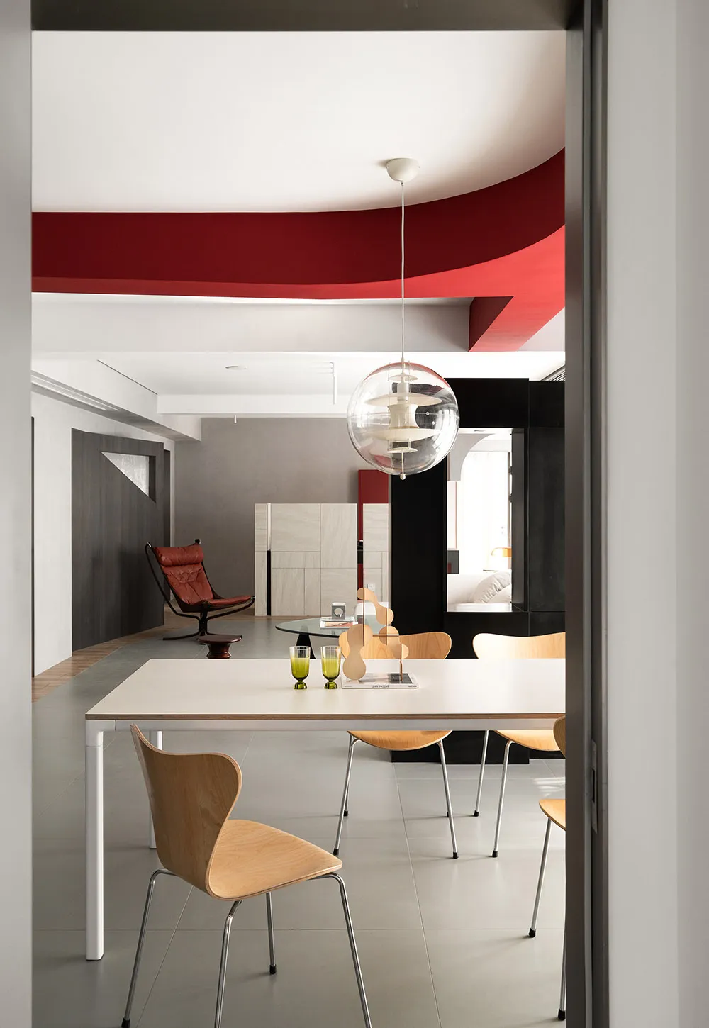 A modern dining room with a table, chairs, and a hanging light fixture.
