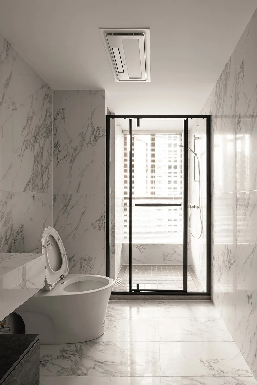 A modern bathroom featuring marble tiles, a glass shower enclosure, and a white toilet.