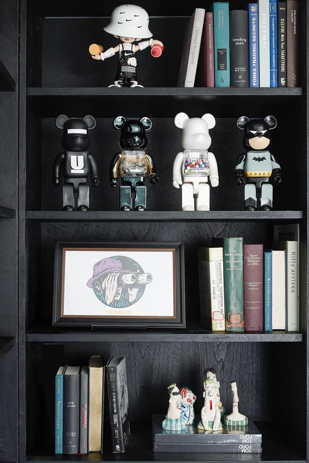 A modern black bookshelf displaying various books, toys, and figurines.