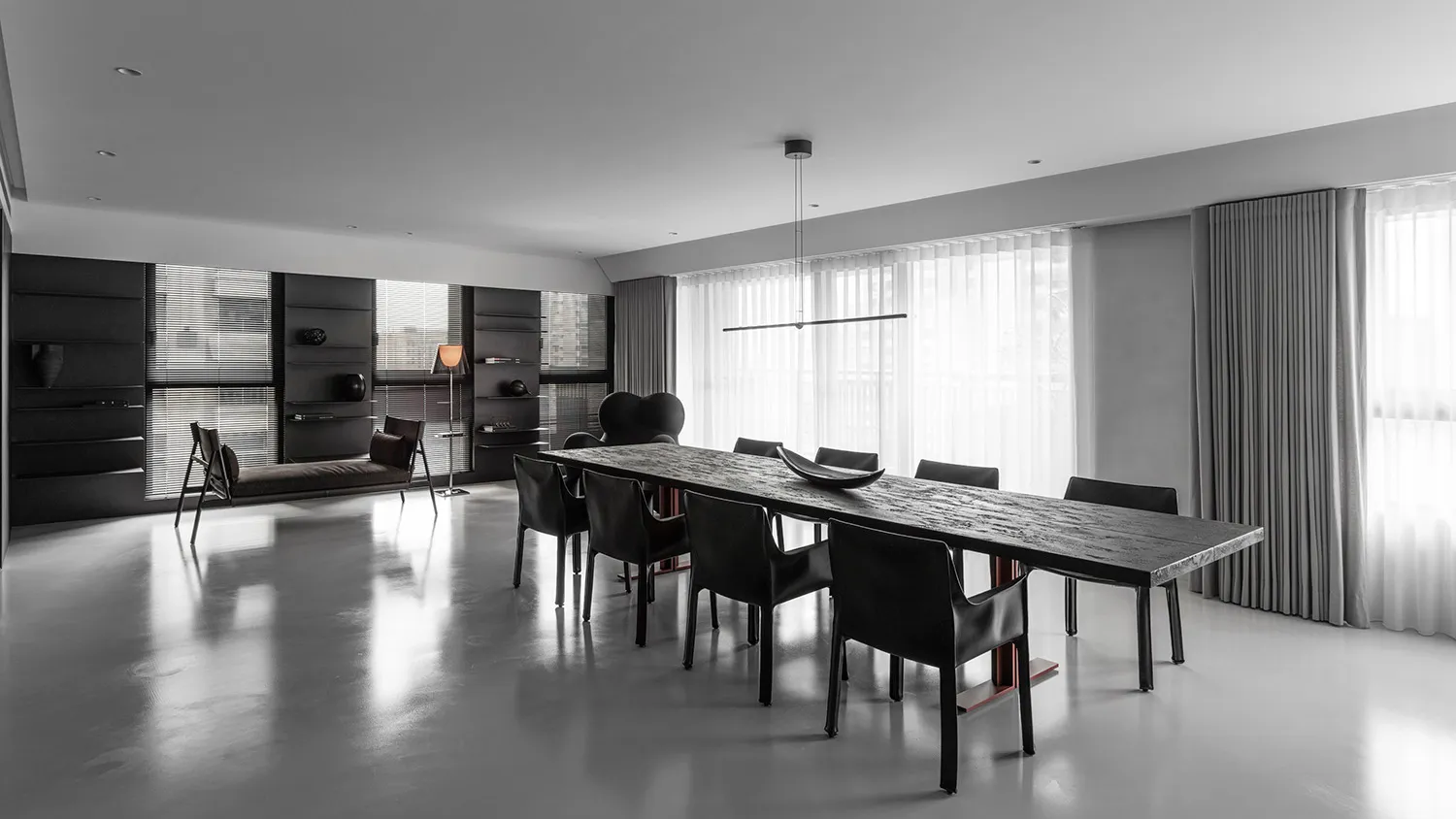 Modern minimalist dining room featuring a concrete table and black chairs.
