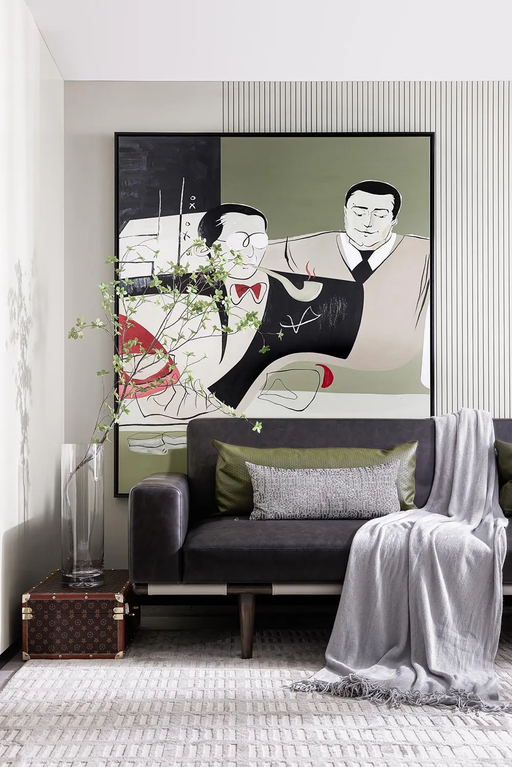 A modern living room featuring a large abstract painting of two men, a sleek gray sofa adorned with olive green and gray cush