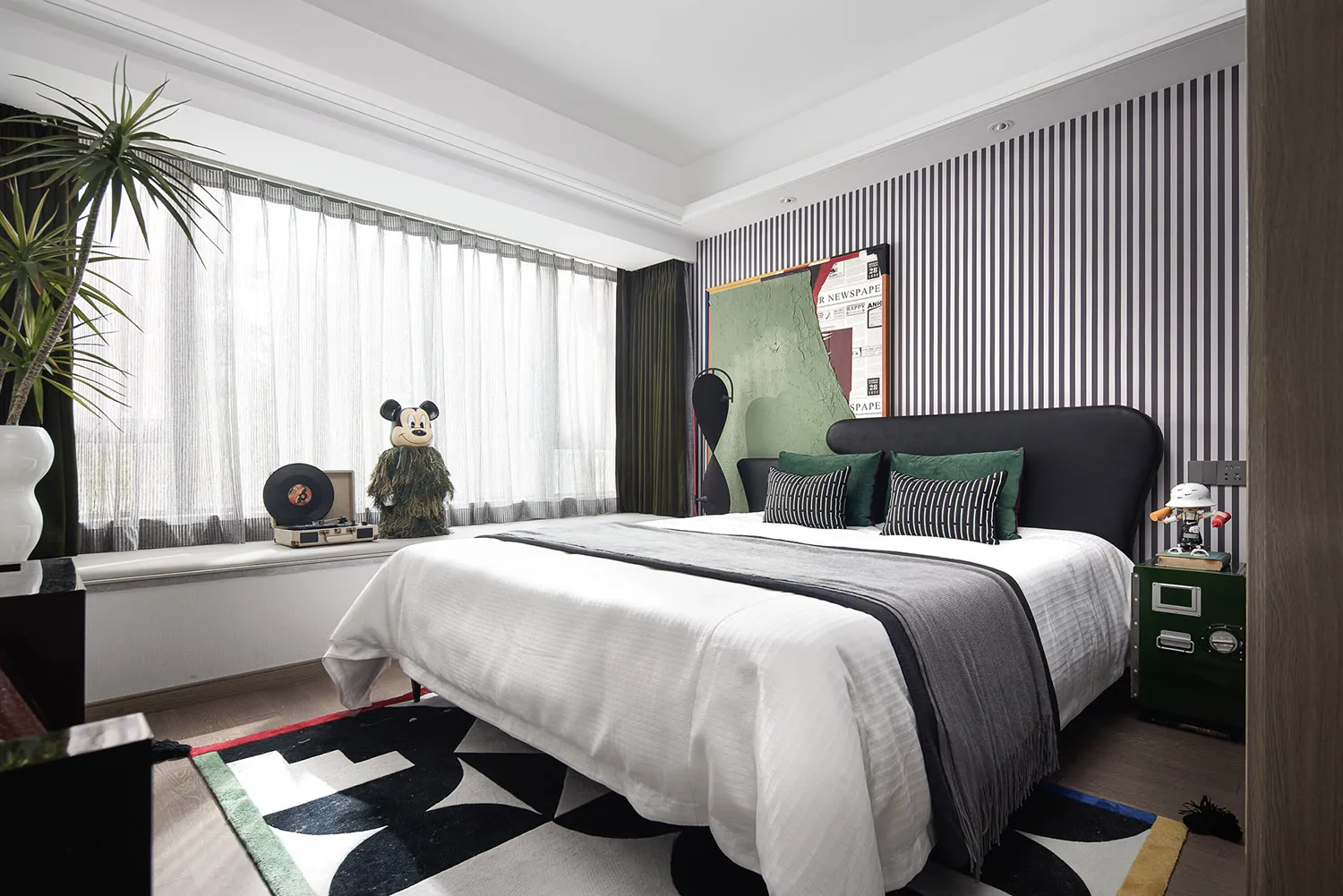 A modern bedroom interior with a white bed, green and black accents, and a striped wall.