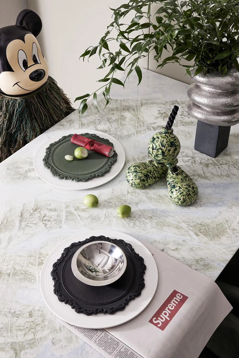 Modern dining room with marble surface, featuring green and black ceramic decorative items and a Mickey Mouse mascot.