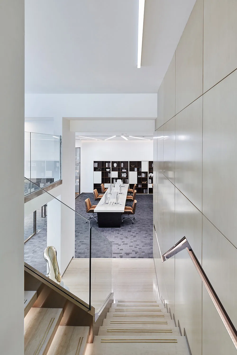 A modern office library space featuring neutral-colored walls and flooring with a minimalist design.