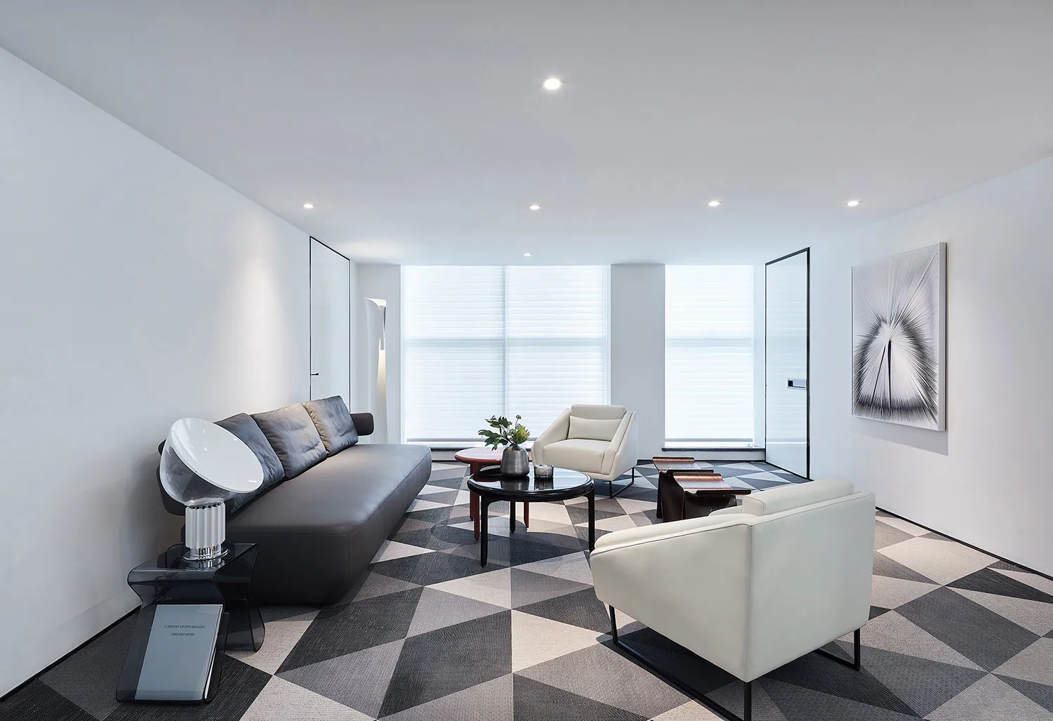 Modern minimalist living room with a geometric patterned floor, white walls, and white and black furniture, featuring a large