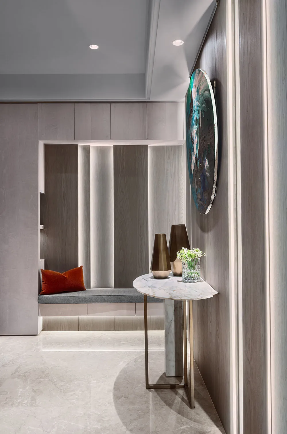 A modern entrance hall featuring marble flooring and wooden walls with a cushioned seating area and decorative elements.